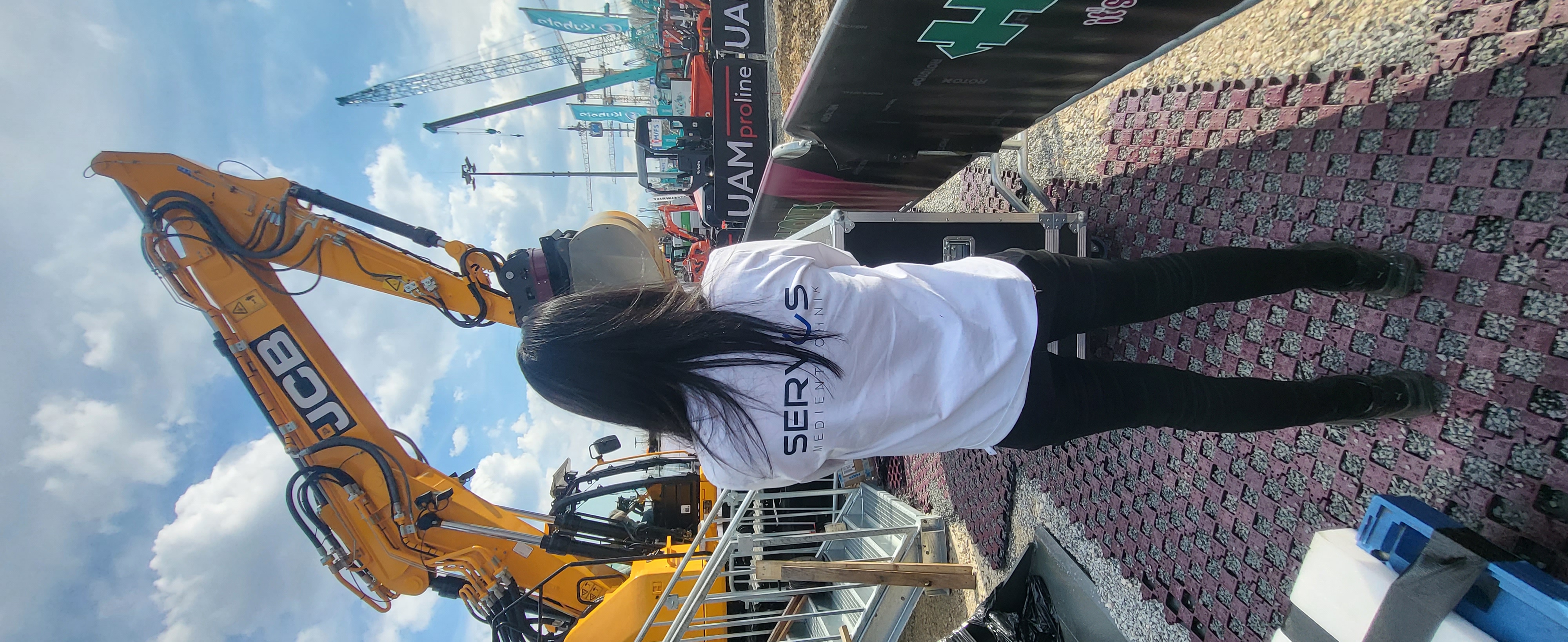 Servus-Mitarbeiterin im Firmen-Shirt bei Display-Aufbau auf einer Outdoor-Baumesse