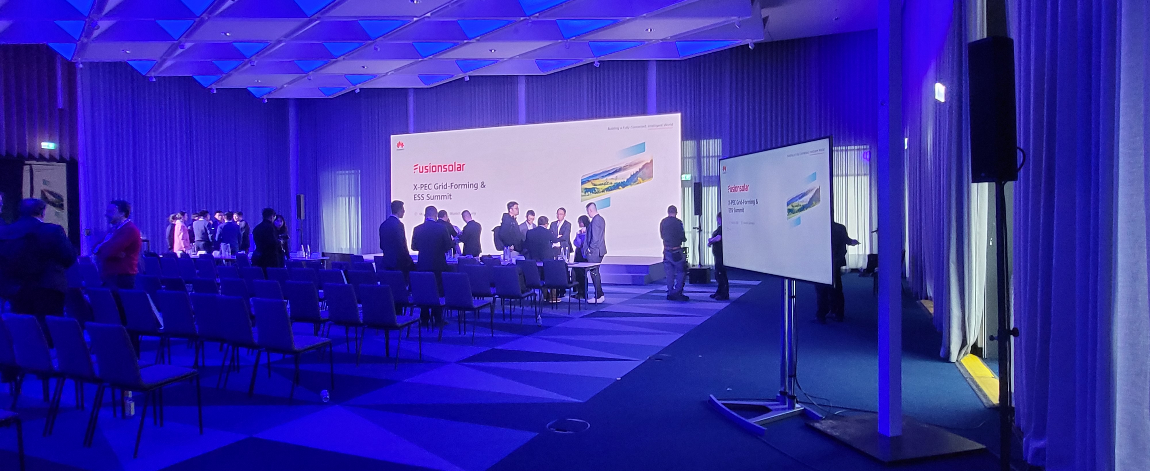 Konferenzsaal mit großer LED-Wand und seitlichen Monitoren für einen Summit