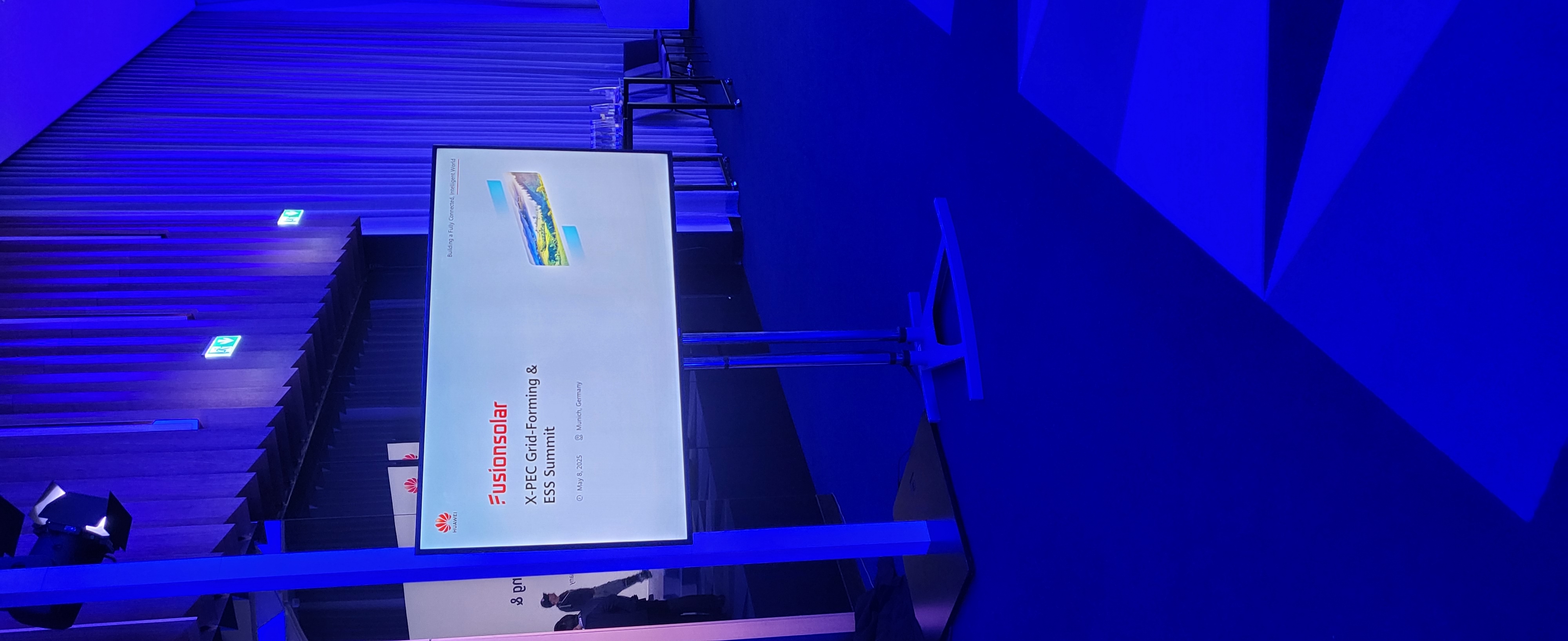 Display in einem blau beleuchteten Konferenzsaal von der Empore aus gesehen