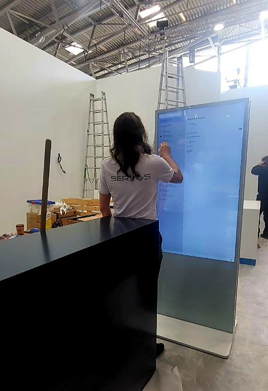 Servus-Mitarbeiterin richtet einen Touchscreen auf einer Messe ein