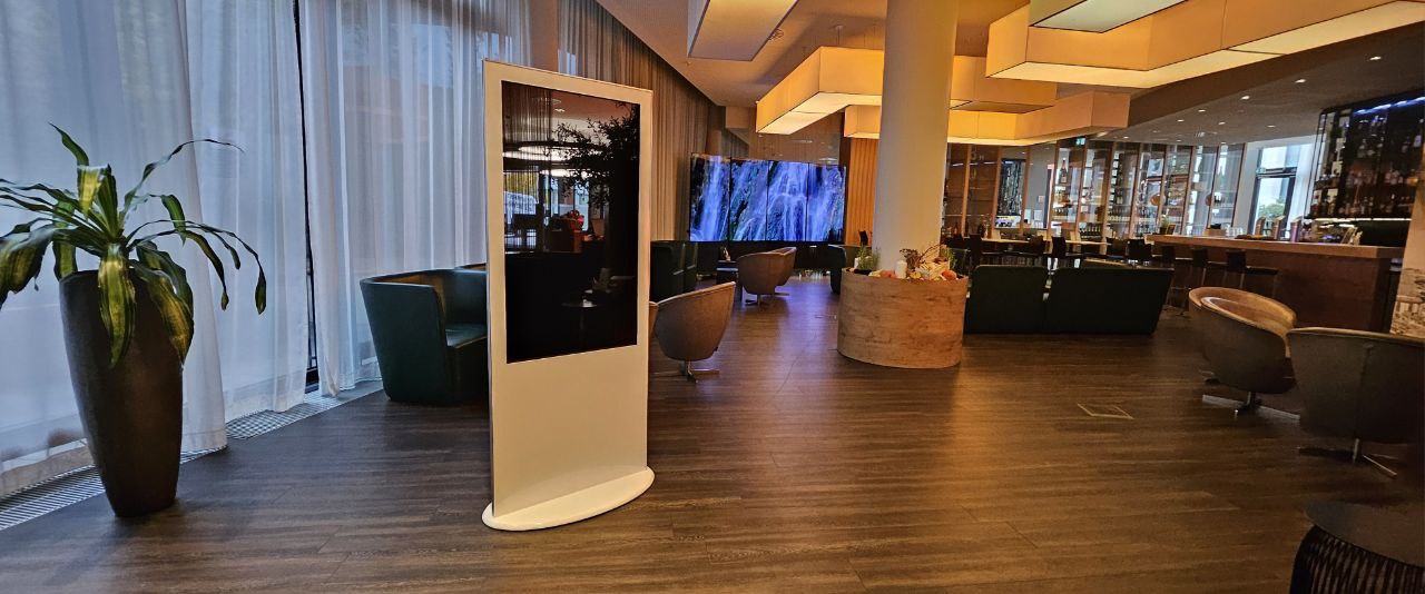Digital-Signage-Stele und LED Wall mit Wasserfallmotiv in einer eleganten Hotel-Lobby